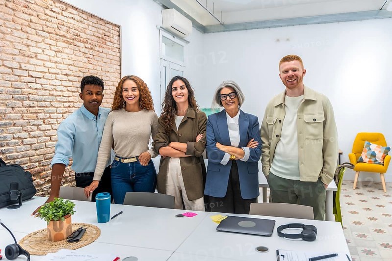 Group of multi ethnic business people posing together in a bright, contemporary office space, symbolizing teamwork, collaboration, and professional success