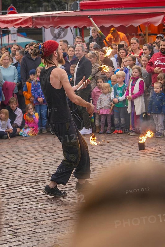 A fire-breather juggles in front of a colourful audience at a festival, Feuernacht, Sindelfingen, Germany