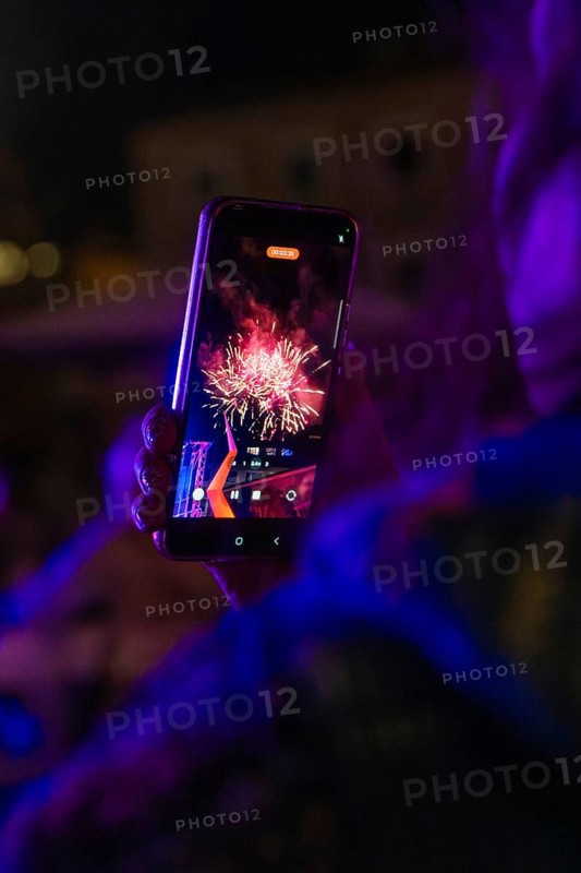 Person holding a mobile phone showing a photo of colourful fireworks at night, Fire Night, Sindelfingen, Germany