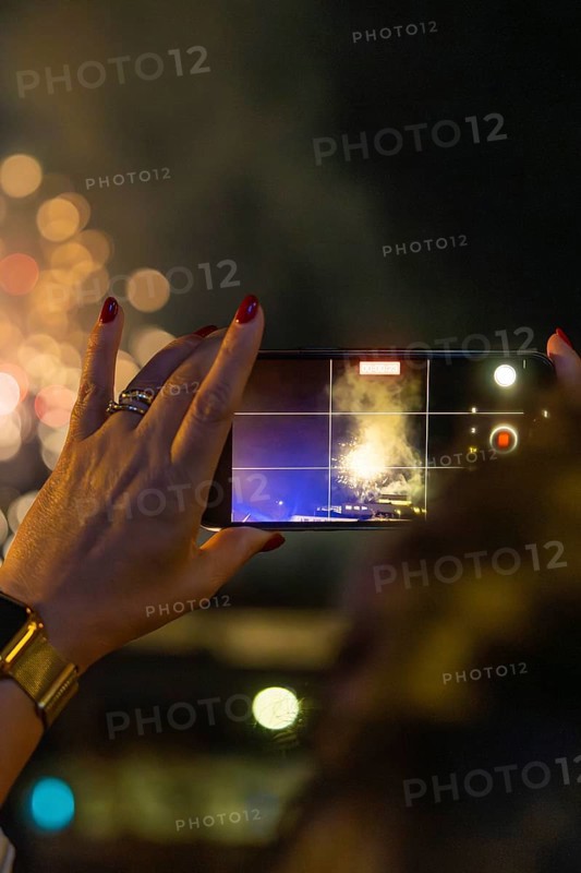 A hand with a mobile phone holds the fireworks in the night, sparkling bokeh, Fire Night, Sindelfingen, Germany