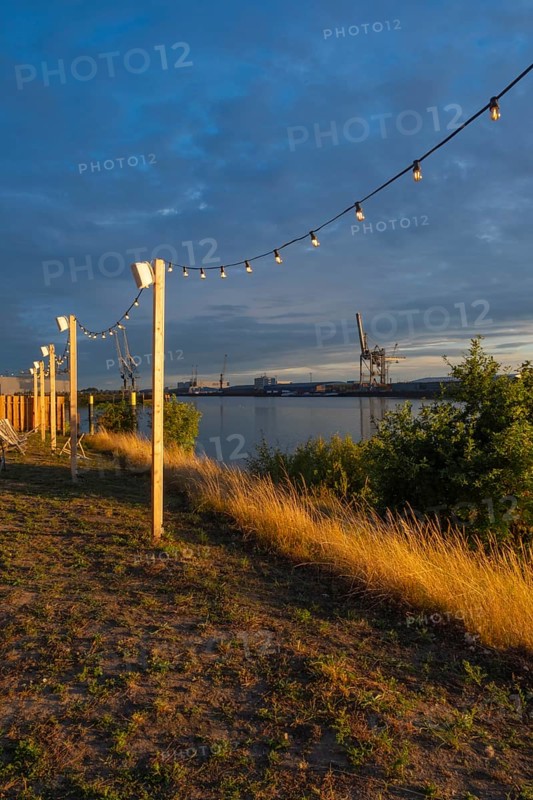 View from the outside area of a restaurant at Lankenauer Höft through a string of lights onto Neustadt harbour in the evening light, Weser, Bremen, Germany
