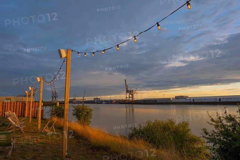 View from the outside area of a restaurant at Lankenauer Höft through a string of lights onto Neustadt harbour in the evening light, Weser, Bremen, Germany