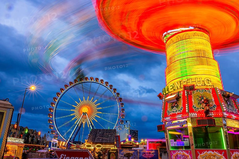 Illuminated chain carousel in motion, behind the Ferris wheel at standstill, Festwiese, Theresienwiese, Oktoberfest, Munich, Upper Bavaria, Bavaria, Germany
