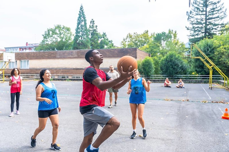 Group of diverse basketball players enjoying a lively game on an outdoor court, highlighting teamwork, athleticism, and the pure joy of engaging in sports with friends