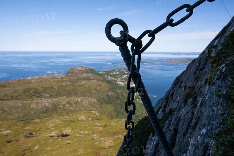 View over coastal landscape with offshore islands, silhouette, hook of a via ferrata in the foreground, island Otroya or Otrøya, Møre og Romsdal, Norway