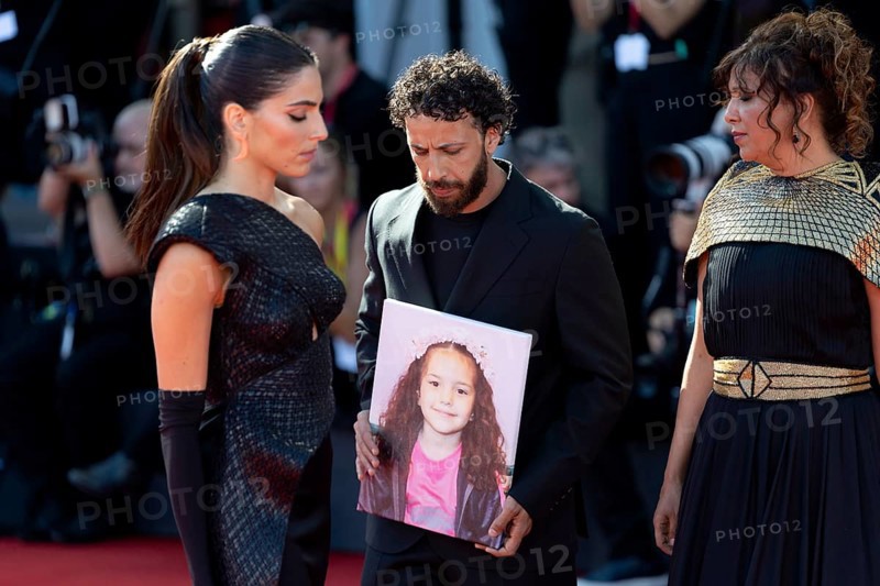 Venice, Italy - 3 September 2025: Kaouther Ben Hania (R) and Saja Kilani (L) and Motaz Malhees (C) with a portrait of five-year-old Palestinian girl Hind Rajab, who was killed by the Israeli army in the Gaza Strip in January 2024, during the Red Carpet of - The Voice Of Hind Rajab - during the 82nd Venice International Film Festival