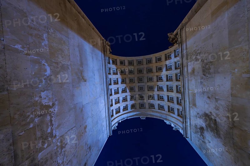 View through a high arcade into the night sky with grid structure, Siegestor, Munich, Germany