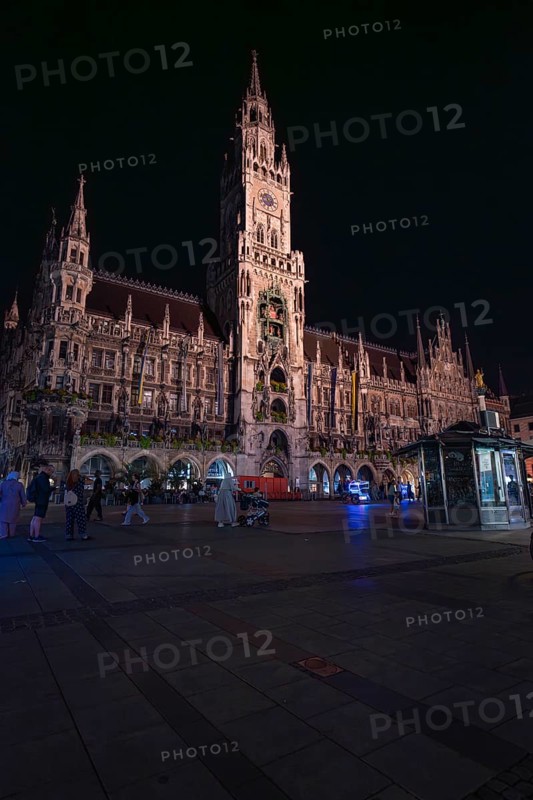 Historic building at night with lighting, people walking around, Munich, Germany