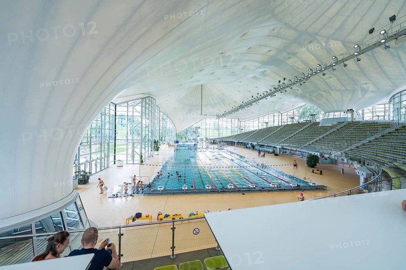 View from above of a modern swimming pool with grandstands and lots of glass, Olympiabad, Munich, Germany