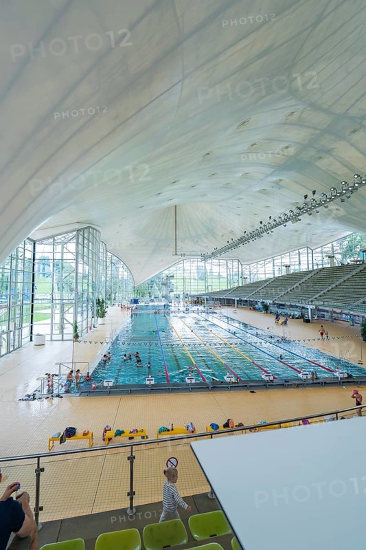 Modern swimming pool with glass façade and seating in a bright atmosphere, Olympiabad, Munich, Germany