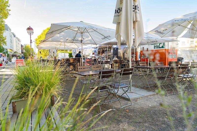 Cosy street café with empty tables and chairs under large parasols, surrounded by green plants, Sindelfingen, Böblingen district, Germany