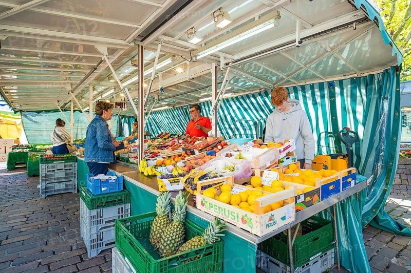 People buying fresh fruit at a colourful market stall under a striped market tent, Sindelfingen, Böblingen district, Germany