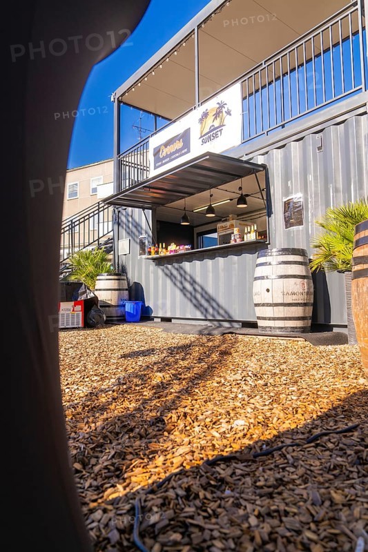 A sunny snack stand made from a container with barrels on a wooden chipboard floor, open air cinema Sindelfingen, district of böblingen, Germany