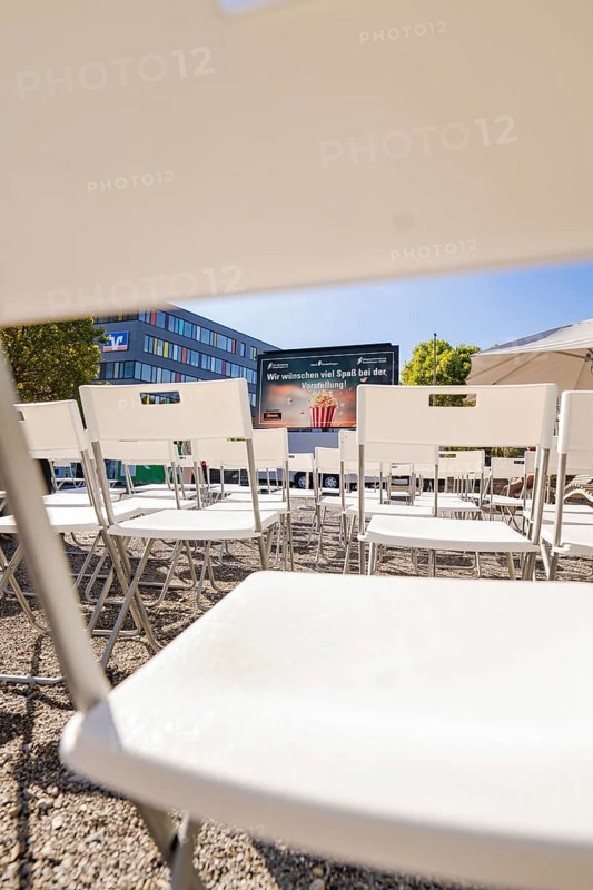 White chairs arranged in rows with a view of a screen and a building in the background, open air cinema Sindelfingen, district of böblingen, Germany