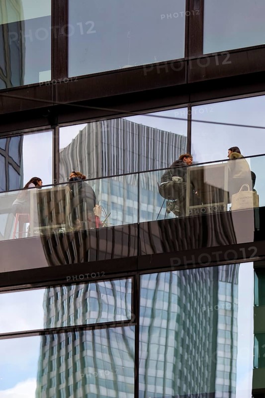 People on the glazed outdoor balcony in a bar with reflection of a skyscraper, Frankfurt am Main, Hesse, Germany