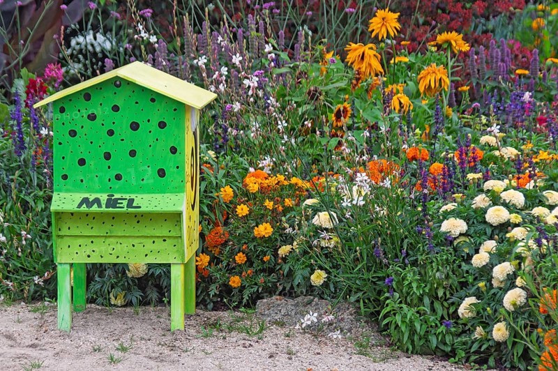 Green beehive in a colourful flowerbed, Brittany, France