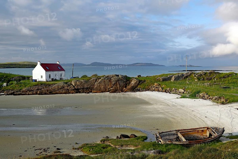 A lonely house and an old boat on a quiet, rocky beach, Isle of Barra, Hebrides, Scotland, United Kingdom
