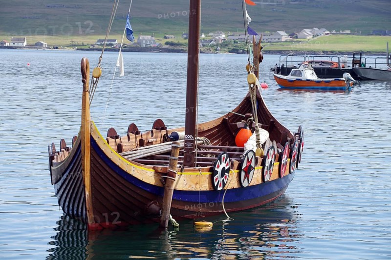 A traditional Viking boat lies decorated in the calm waters of a harbour, Lerwick, Shetland, Shetland Islands, Scotland, United Kingdom