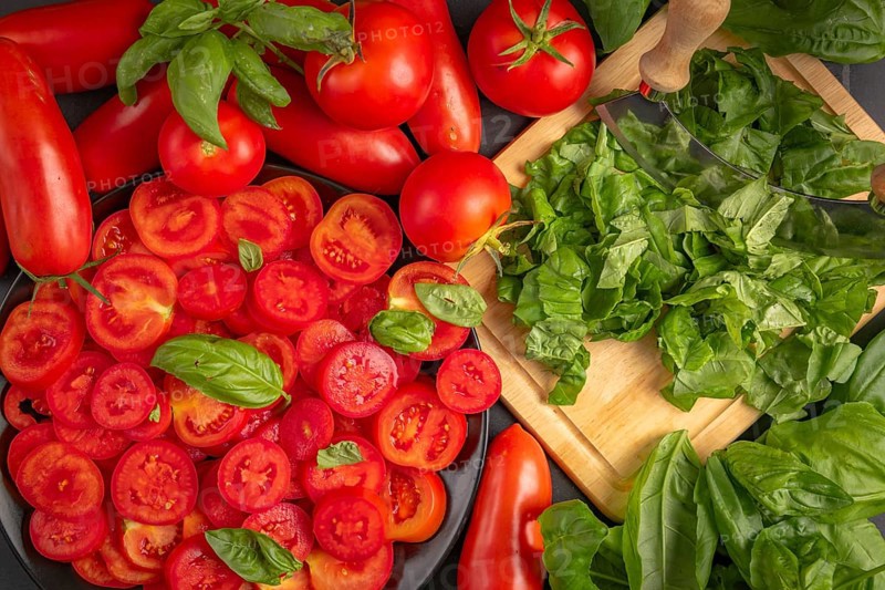 Fresh tomatoes and basil leaves on a chopping board, in bright red and green colours