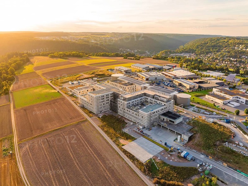 Modern building surrounded by fields and surrounding hills at sunset, new hospital building, Calw health campus, Black Forest, Germany