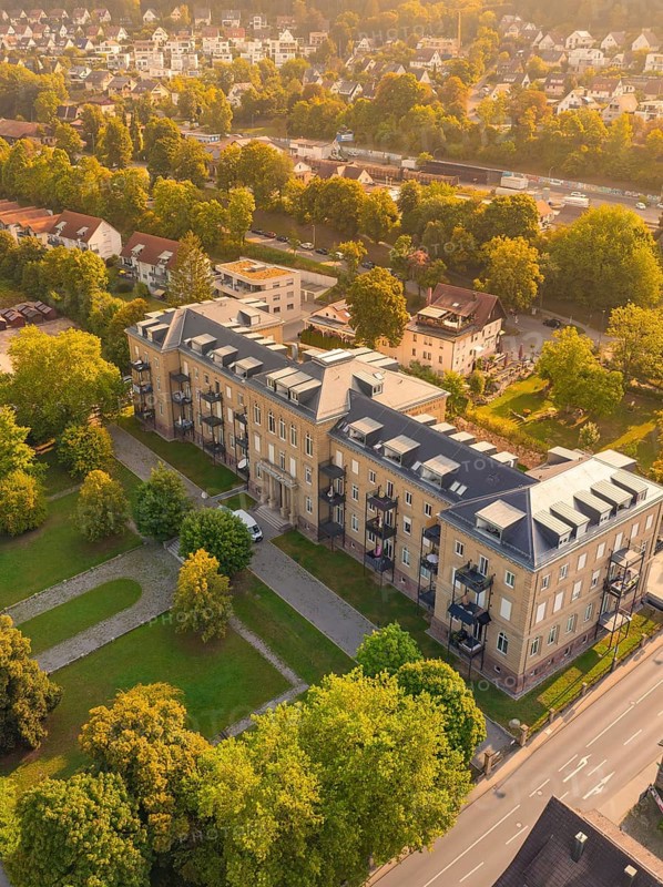 Large building with flat roof and balconies, surrounded by trees and streets in a sunny neighbourhood, small town of Perle Nagold, Black Forest, Germany