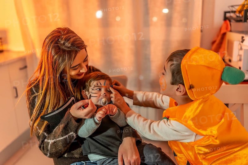 Mother and son applying halloween makeup on baby brother, getting ready for trick or treating