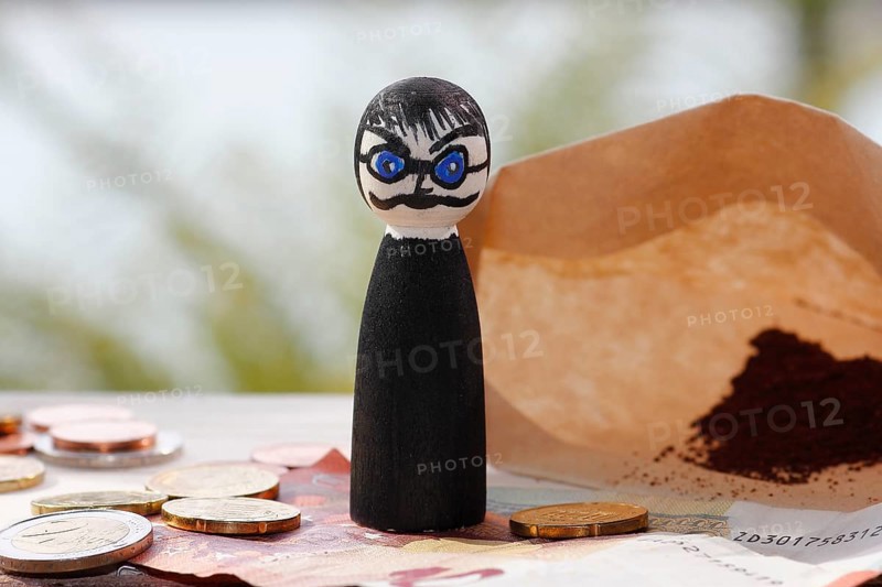 Male wooden cone figure with coins and banknote in front of filter bag with coffee North Rhine-Westphalia, Germany
