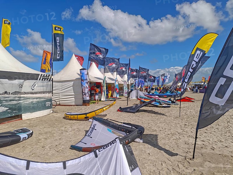 California kitesurfing Masters 2025, Kite Village tents with kite equipment for sale, marketplace, try out, kitesurfing on the North Sea beach, blue sky, sun, summer, Ording, Sankt Peter-Ording, Schleswig-Holstein, Germany