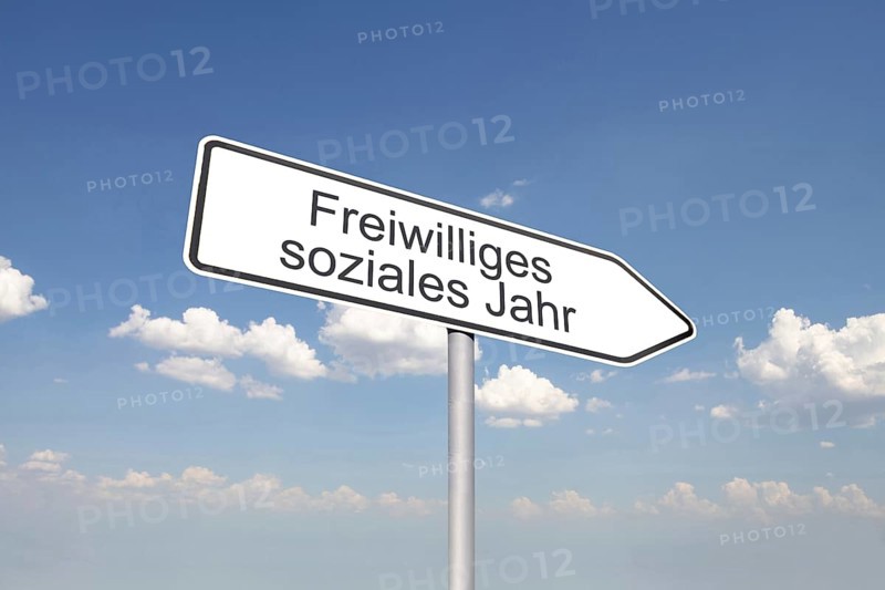(Photomontage) Directional arrow with the inscription VOLUNTARY SOCIAL YEAR against a blue sky