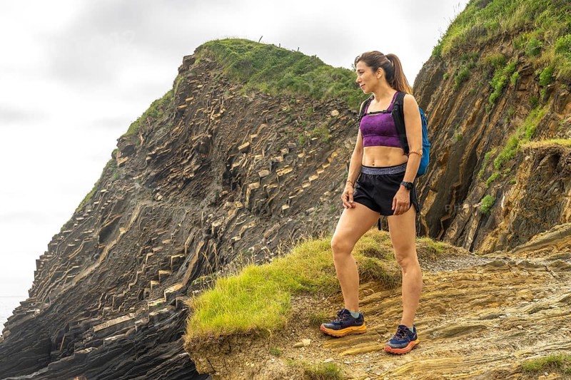 Female hiker admiring the breathtaking flysch cliffs at sakoneta beach in zumaia, gipuzkoa, a unique geological formation on the basque coast