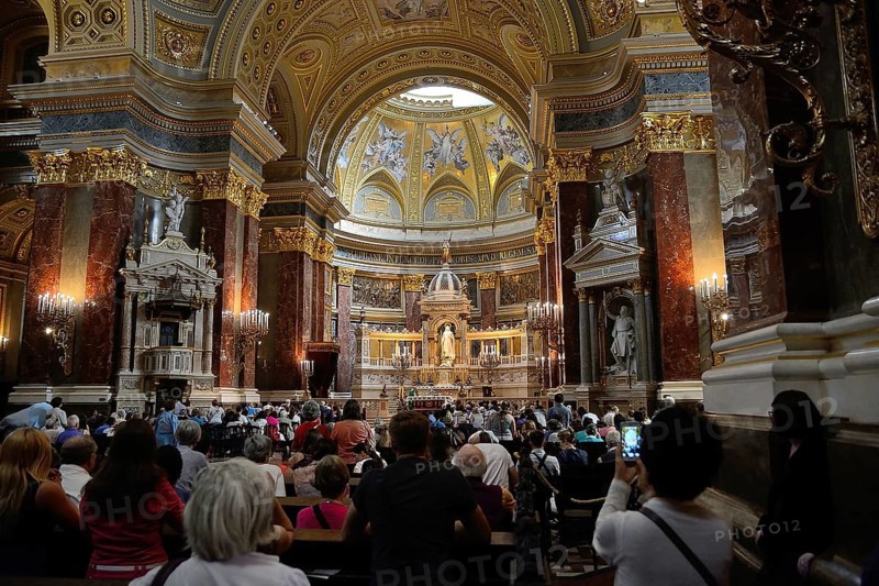 Tourists and locals are attending a mass in st. Stephen's basilica, a romanesque catholic basilica in budapest, hungary