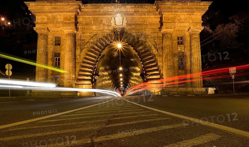 Long exposure photo of cars driving into a tunnel in budapest at night, creating streaks of light