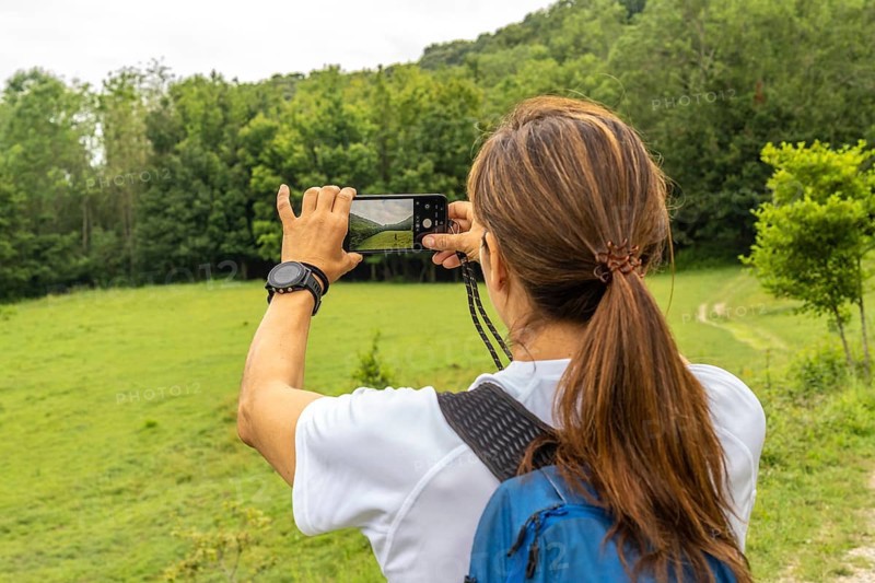 Female hiker taking pictures of the landscape with her smartphone in sakoneta beach area and its coastal flysch in zumaia, basque country