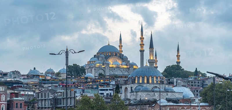 Majestic suleymaniye mosque glowing under cloudy sky at dusk, showcasing istanbul's rich history and architectural beauty
