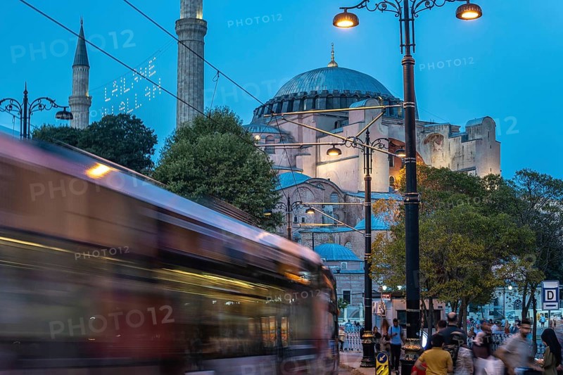 Tram gliding past the iconic hagia sophia in sultanahmet square during the enchanting blue hour in istanbul, turkey