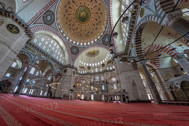 Wide angle view of the suleymaniye mosque interior in istanbul, turkey, showing the vastness of the space, intricate design and red carpet