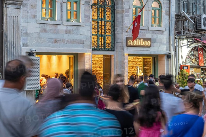 People walking on the street in front of a busy restaurant in istanbul, turkey, in motion blur