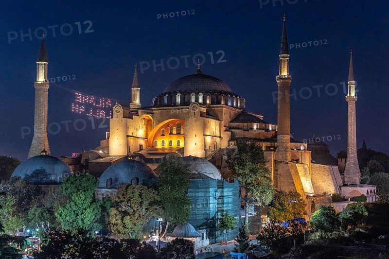Hagia sophia illuminated at night with a drone light show displaying a religious message in the sky above istanbul, turkey