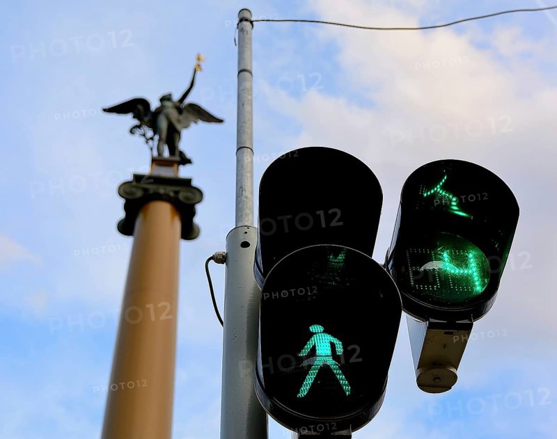 Green traffic light allows pedestrians to cross the street in budapest, hungary, with a statue visible in the background
