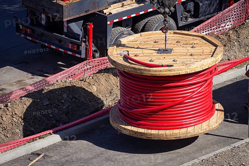 Big red cable coil, rises for installation at the city construction site, no people