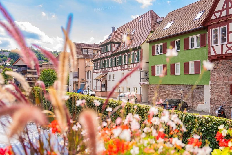 River view along half-timbered houses and flowers in sunny, idyllic surroundings, small town pearl Calw, Black Forest, Germany