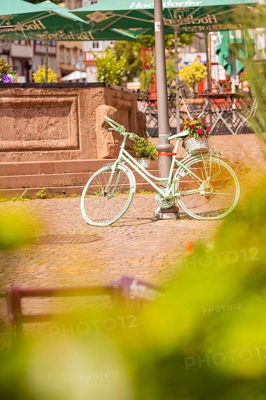 A white bicycle stands decoratively in front of a fountain in the town, small town of Perle Calw, Black Forest, Germany