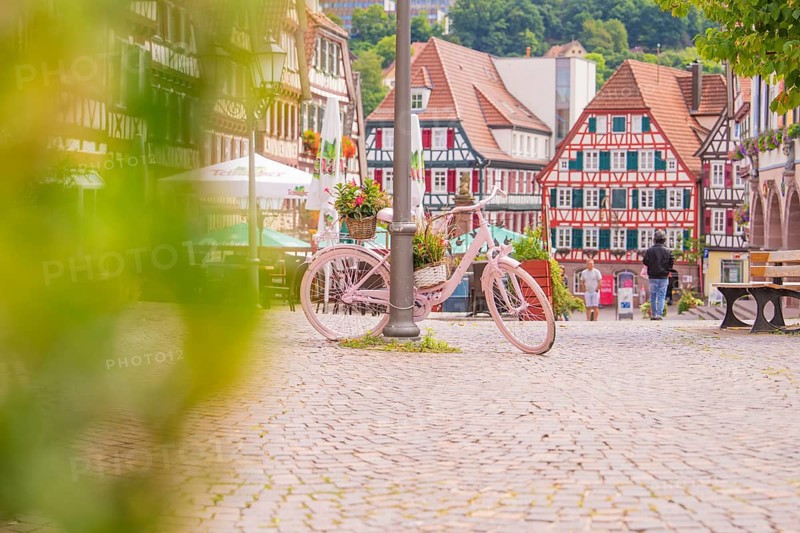 Pink bicycle with flowers in the foreground of a picturesque half-timbered old town with cobbled streets, small town pearl Calw, Black Forest, Germany