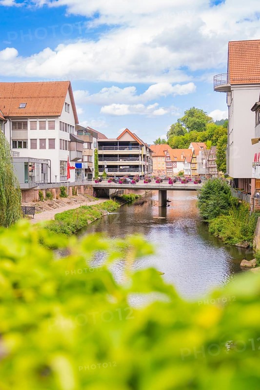 Urban river with modern architecture and bridges, surrounded by summer vegetation, small town pearl Calw, Black Forest, Germany