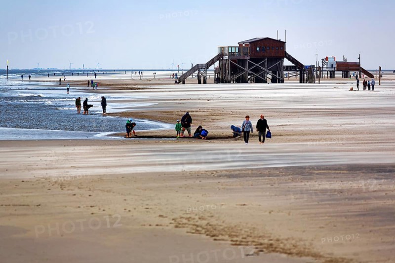 Walkers on the beach, pile dwelling and Westerheversand lighthouse on the horizon, wind, Sankt Peter-Ording, Eiderstedt peninsula, Wadden Sea National Park, North Sea, North Frisia, Schleswig-Holstein, Germany