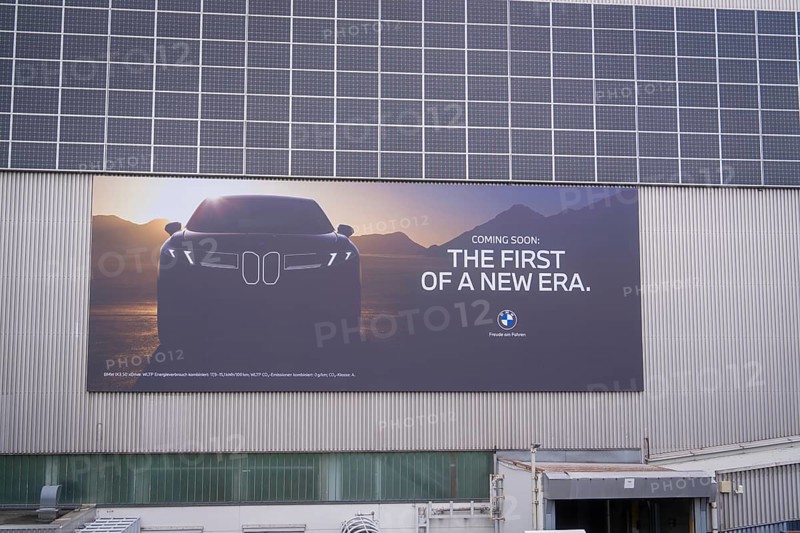 Large poster with car design and announcement in front of a wall with solar cells, BMW Welt, Munich, Germany