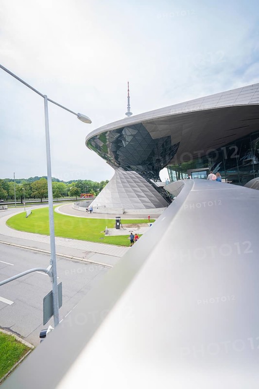 Futuristic building with green area in the foreground, next to a busy road, BMW Welt, Munich, Germany