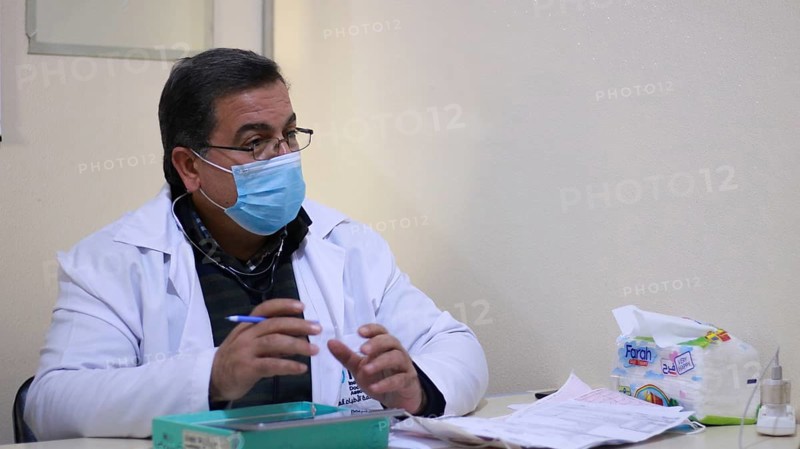 A Syrian doctor wearing a protective mask consults with a displaced patient inside a medical clinic. Aleppo, Syria May 28, 2022, Aleppo, Syria