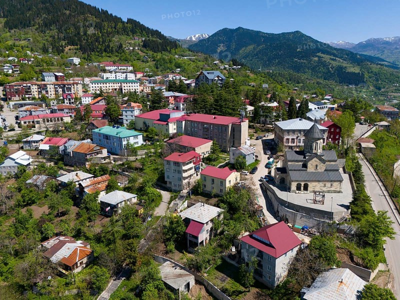 Small town with colourful houses and church, surrounded by green mountains under a clear sky, aerial view, Khulo, Chulo, Autonomous Republic of Adjara, Adjara, Lesser Caucasus, Georgia