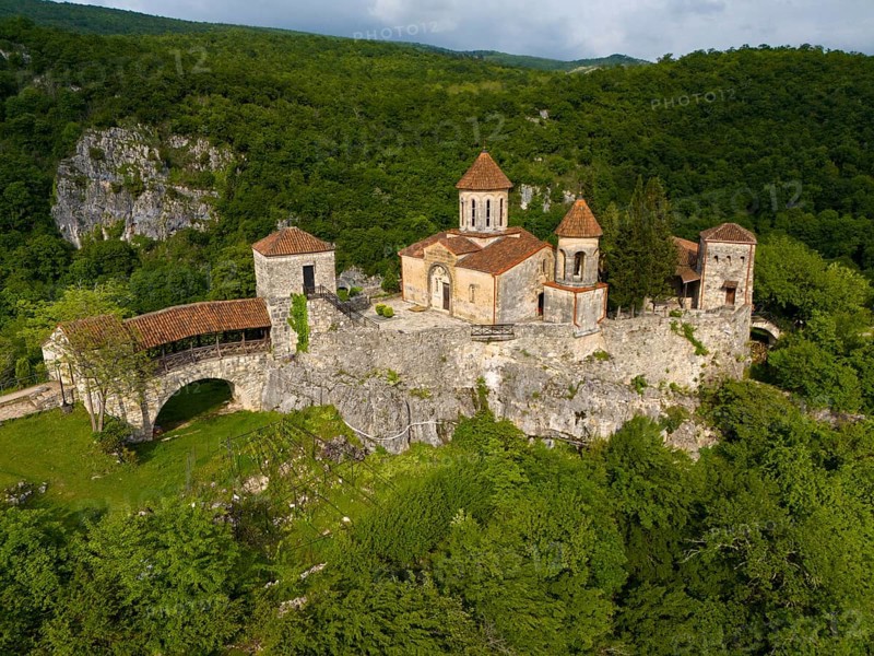 Spacious monastery structure on a rock surrounded by forest landscape, aerial view, Motsameta Monastery, near Kutaisi, Imereti region, Georgia